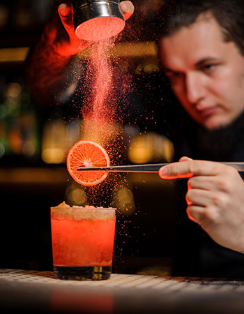 mixologist making a drink with an orange slice